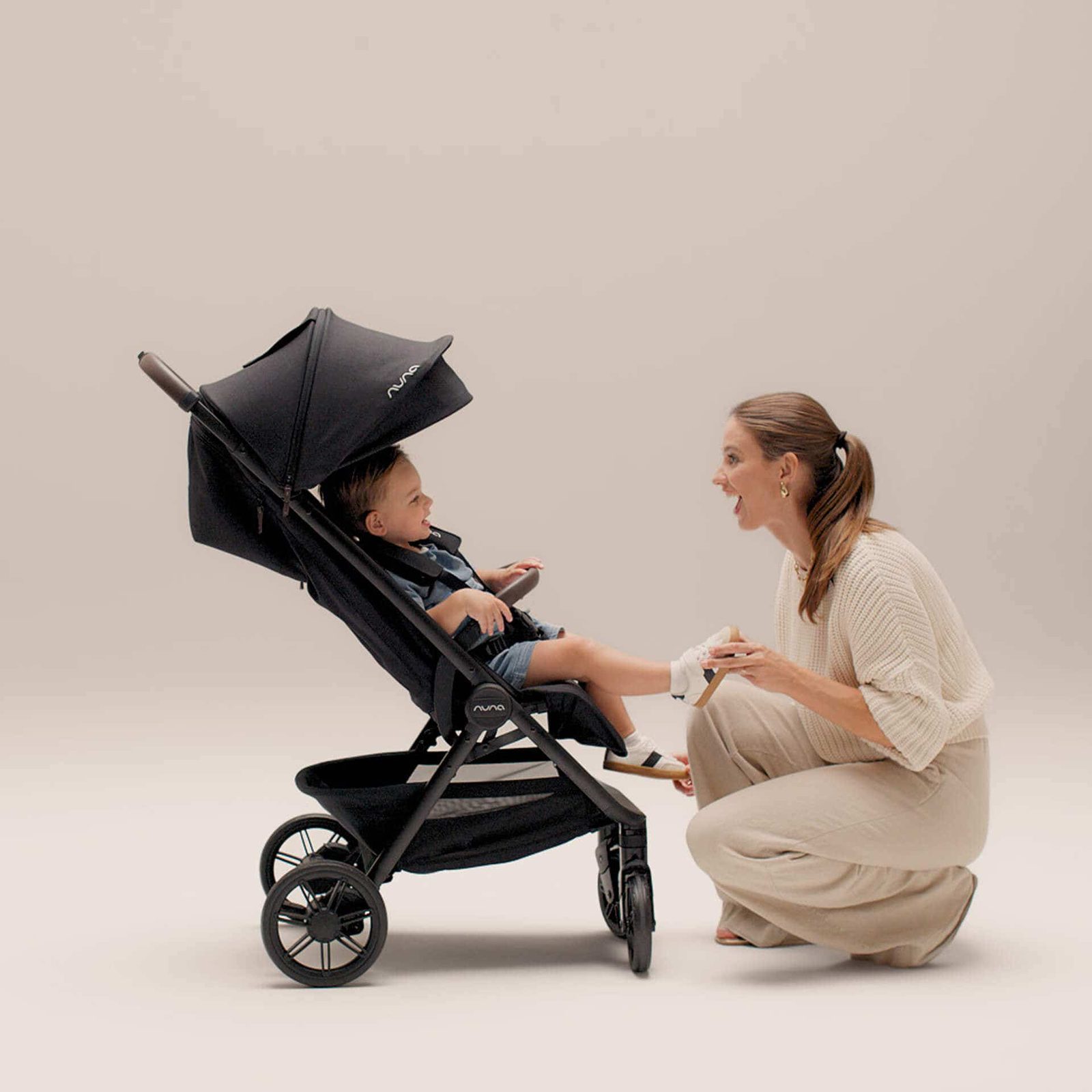 Mum walking with a toddler in the Nuna Trvl Urbn compact stroller in Caviar black