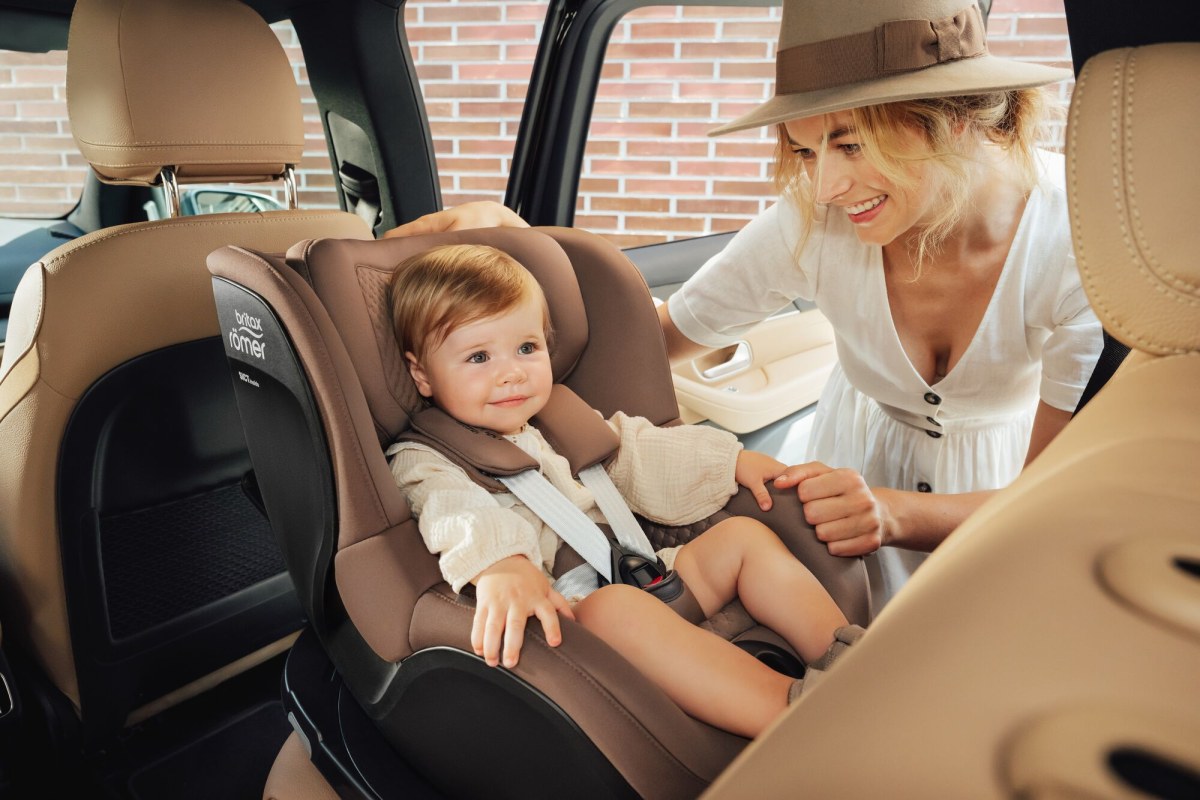 A mother beside her toddler travelling rear-facing in a Britax Römer car seat