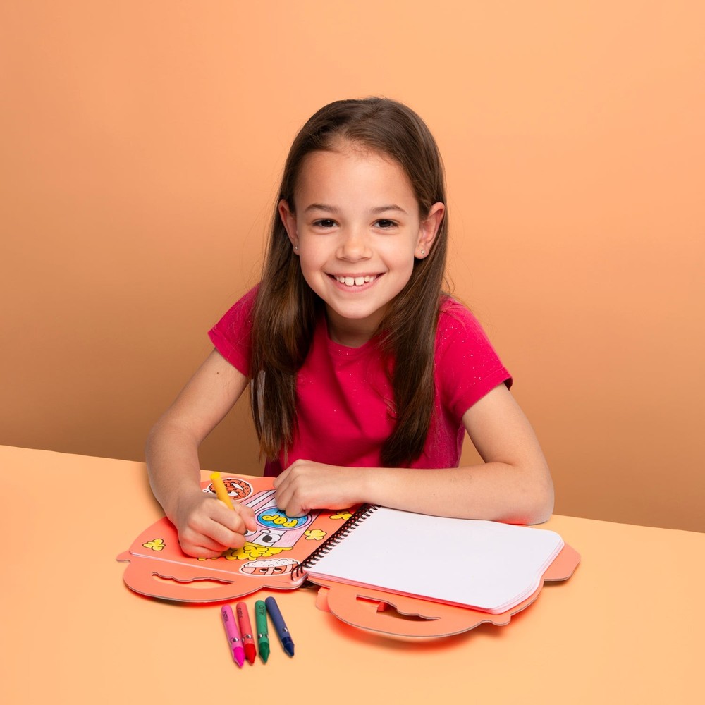 A smiling girl colouring with an OMY creative set at a table