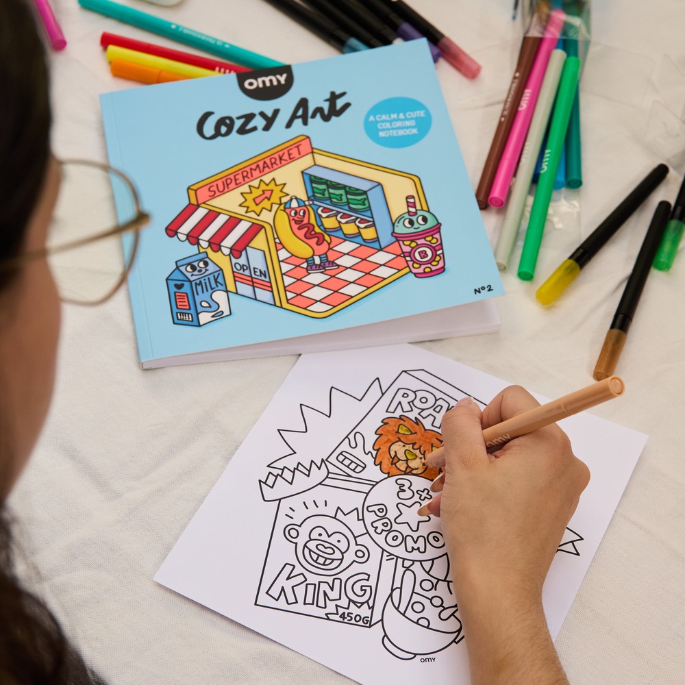 A child colouring a detailed OMY illustration with felt-tip markers