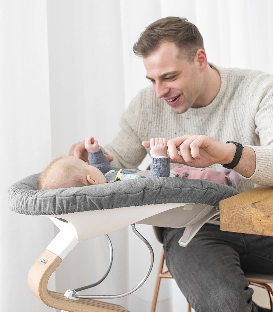 A parent at the table beside a newborn in the Stokke Nomi Newborn Set