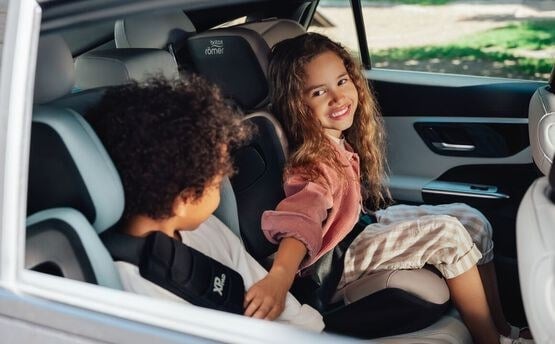Two children seated side by side in Britax KIDFIX PRO boosters — slim design fits three across