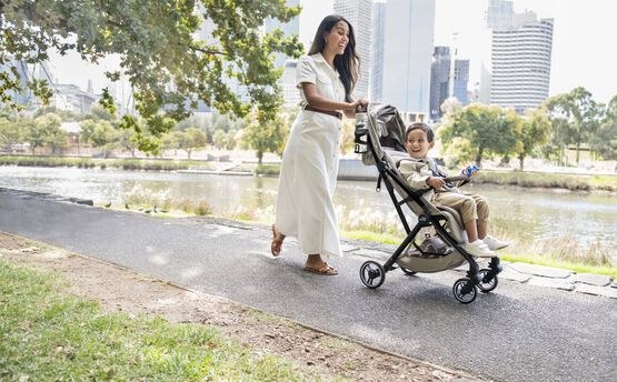 A parent strolling with the Britax Flylite along a city riverside